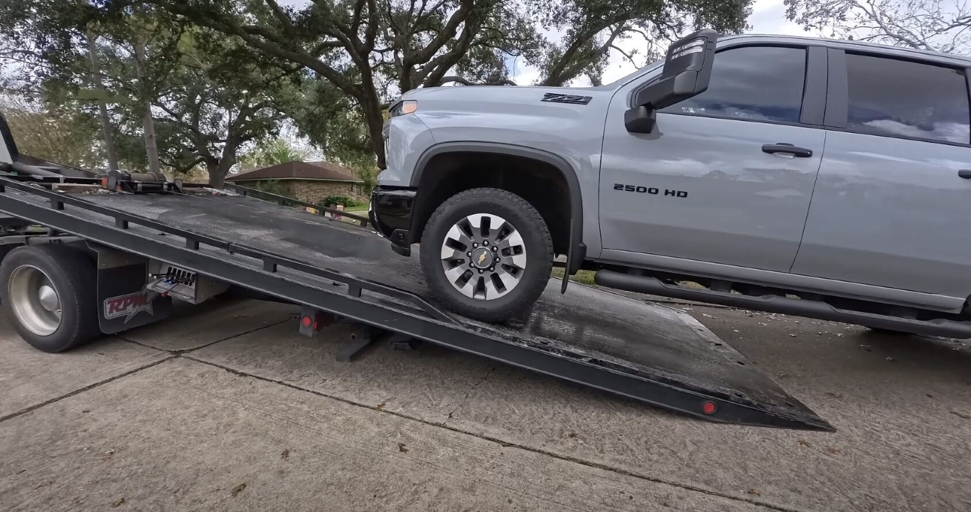 Flatbed towing service transporting silver truck safely